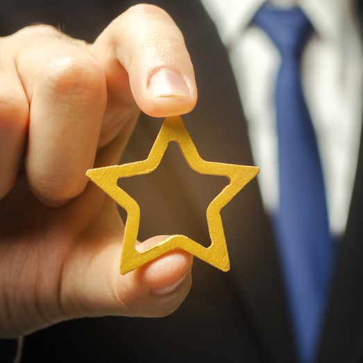 Man holds a golden star in his hand. Symbol of success and excellence. Good reputation, prestige, high recognition. Status, rating. Good ratings and reviews. VIP. Job promotion and career growth.